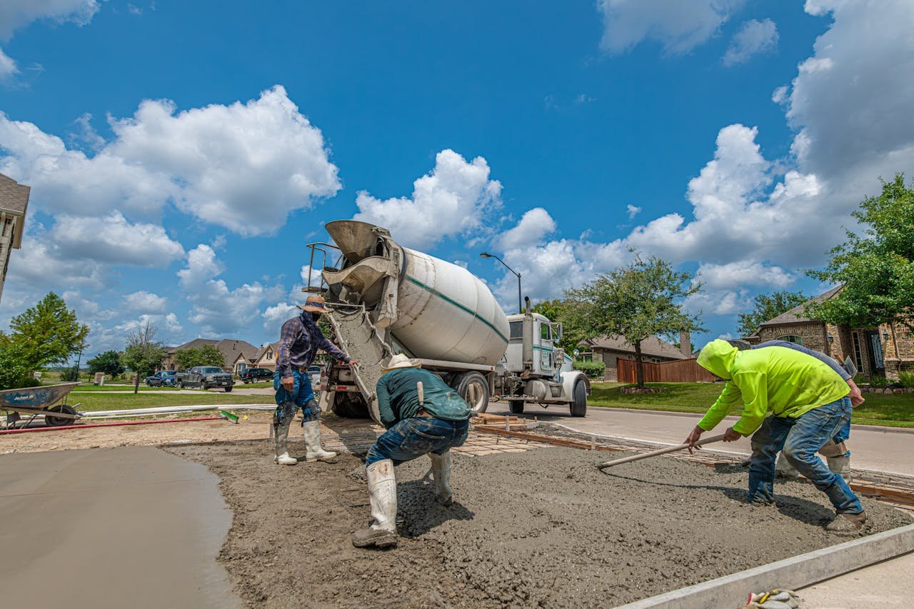 Construction workers laying concrete for a driveway in Fort Worth, Texas, under a bright blue sky.